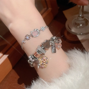 Detail of layered silver bracelets featuring pink opal Hello Kitty and heart zircon charms