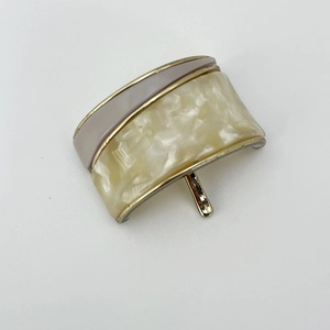 Detail of minimalist hair cuff with cream pearl texture and grey resin on gold finish