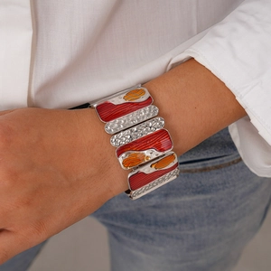 Detail view of multi-segment silver metal bracelet with red and orange enamel patterns