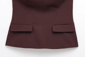 Dettaglio ravvicinato di un top a fascia bordeaux con tasche a patta e orlo rifinito
