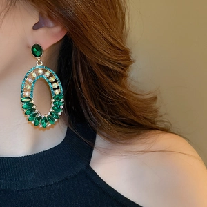 Close-up of emerald green oval crystal drop earrings with sparkling pavé details