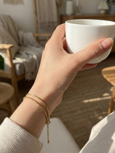 Detail of 18k gold plated double-layer snake and bead chain bracelet on a woman wrist