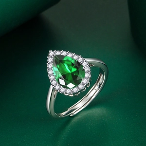 Close-up of a pear-cut emerald green gemstone ring with halo diamonds and adjustable band