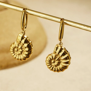 Golden sea shell drop earrings featuring spiral nautilus pendants on polished hoops