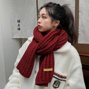 Detail of burgundy chunky knit scarf with a leather hand made tag and cable stitch texture