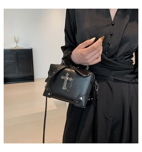 Detail of gothic black PU leather handbag with vintage silver cross and metal chain decoration