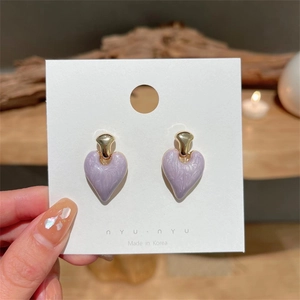 Detail of heart-shaped purple marble earrings with gold claws on a jewelry card