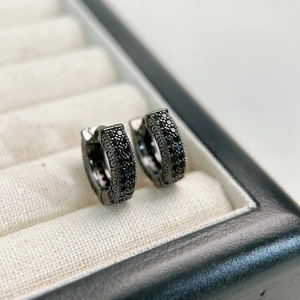 Macro shot of black paved hoop earrings with dark stones in a jewelry box