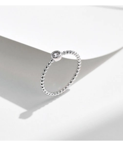 Macro dell'anello con perline d'argento e una scintillante pietra moissanite rotonda colore D