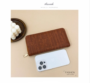 Top view of a brown textured long wallet for women with zipper and smartphone for size