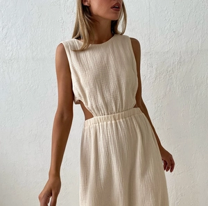 Detail of cream crinkle gauze dress featuring side cut-outs and elastic waist texture