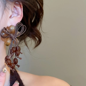Close-up of vintage resin bow earrings with dark amber beads and dangling tassels