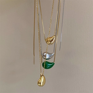 Detailed display of minimalist teardrop necklaces in gold, silver, and green resin finishes