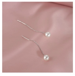 Vue macro de boucles d'oreilles pendantes en argent S925 et perle sur soie rose
