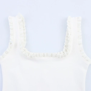 Dettaglio dell'abito in maglia bianca con scollo quadrato e decorazioni di perle