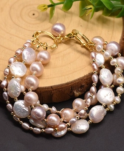 Macro detail of multi-layer baroque freshwater pearl bracelet with golden clasp on wood