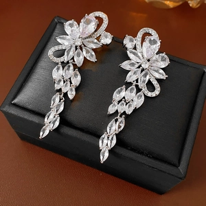 Detailed view of silver floral earrings with sparkling zircon tassels on a black jewelry box