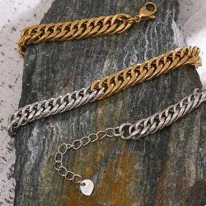 Macro shot of stainless steel curb chains in gold, silver, and dual-tone on grey rock