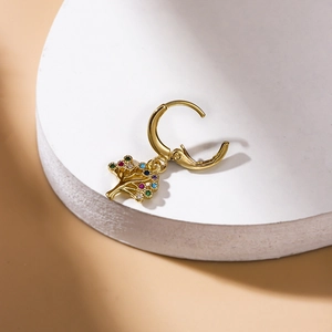 Close-up of golden tree of life earring with colorful zircon crystals on stone stand