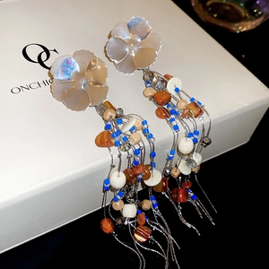 Detail of flower shell resin earrings with colorful bead tassels and metallic chains