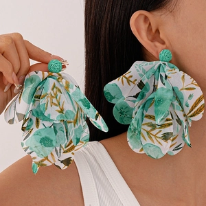 Close-up of lightweight raffia woven floral earrings with green petals and lace details