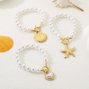 White beaded pearl bracelet set with gold shell starfish and heart charms in beach style