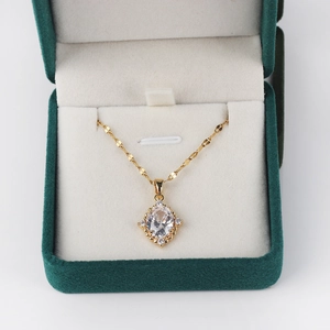 Detail of a gold-plated cross necklace with a large crystal pendant in a green gift box
