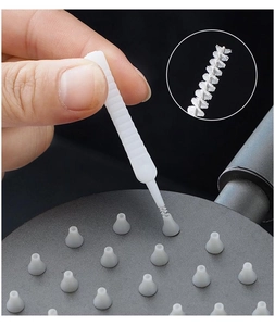 Detailed view of white nylon shower head cleaning brush clearing small nozzle holes