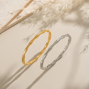 Bracciali in stile bambù placcati in oro 18K e argento presentati su una base in pietra naturale