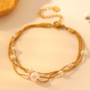 Three-layer stainless steel bracelet featuring gold beads and nine cream pearls
