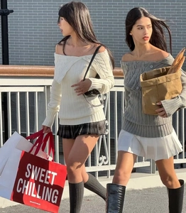 Outdoor shot of stylish off-shoulder cable knit sweaters for women in white and grey colors