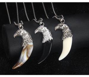 Detailed macro view of wolf tooth necklaces with eagle head charms in three colors