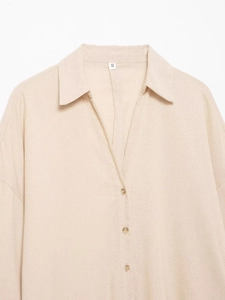 Détail du col d'une chemise en lin beige avec boutonnage et texture de tissu naturel