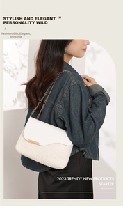 Detail of woven straw shoulder bag featuring a gold clasp and elegant chain strap