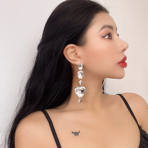Elegant geometric silver drop earrings with heart crystal pendants shown on a model