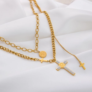 Detailed view of gold double-layer necklace with cross pendants and Saint Benedict medal