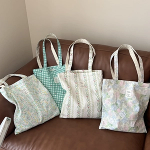 Detail showing four styles of floral and checkered cotton tote bags on a leather sofa