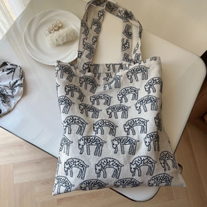 Detailed overhead view of a cream canvas tote bag featuring black sheep embroidery patterns