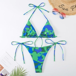 Mise à plat d'un bikini camouflage tropical avec lunettes et feuille de palmier