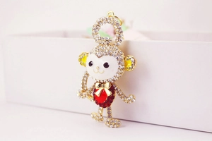 Detail of crystal monkey keychain featuring gold plating, enamel face and red heart