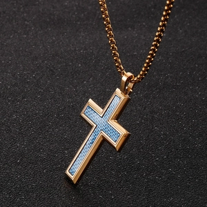 Macro shot of gold cross pendant featuring blue carbon fiber texture and polished edges