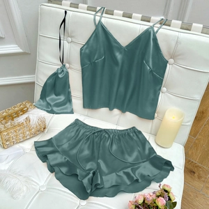 Three-piece satin sleepwear set in dark green with camisole, ruffle shorts and storage bag
