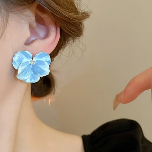 Close-up of light blue flower earrings with rhinestone center on female model