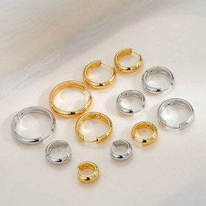 Polished gold and silver hoop earrings in assorted sizes on minimalist silk background