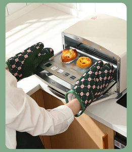 Action shot of heat-resistant floral oven mitts taking a baking tray out of the oven