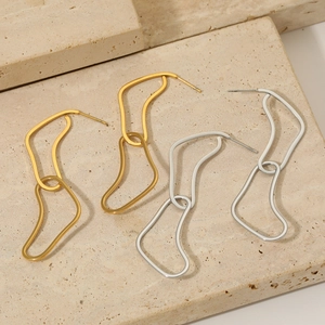 Minimalist geometric curved gold and silver metallic earrings on textured stone base