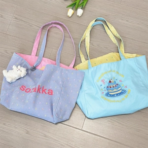Close-up of canvas tote bags featuring vibrant embroidery and colorful checkered lining
