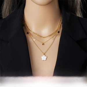 Detail of a three-layer gold-plated necklace featuring shell texture floral pendants