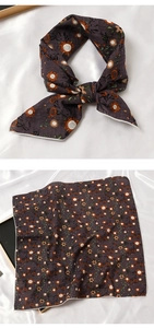 Détail d'un élégant foulard en soie gris foncé à motif tournesol noué en un joli nœud