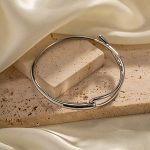 Bracelet jonc minimaliste en acier inoxydable argenté poli sur un socle en pierre